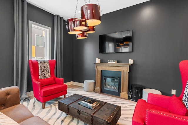 living area featuring a glass covered fireplace and baseboards