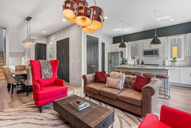 living room with recessed lighting, a notable chandelier, and light wood finished floors