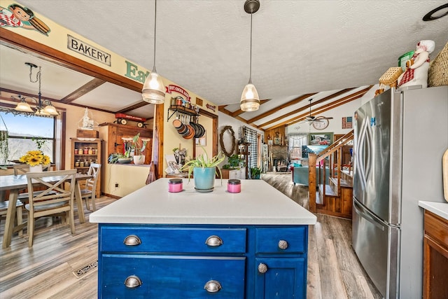 kitchen featuring freestanding refrigerator, vaulted ceiling with beams, a textured ceiling, light wood-type flooring, and blue cabinetry