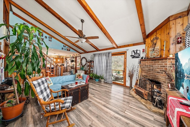 living room featuring vaulted ceiling with beams, a fireplace, wood finished floors, and ceiling fan