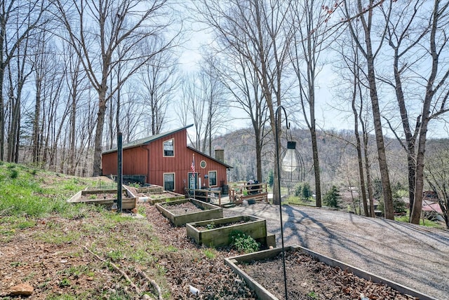 view of yard with gravel driveway, a vegetable garden, and an outbuilding