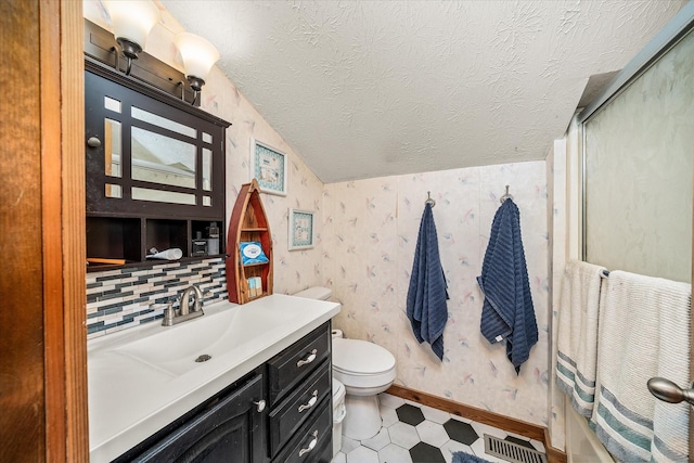 bathroom featuring wallpapered walls, a textured ceiling, lofted ceiling, a shower with shower door, and visible vents