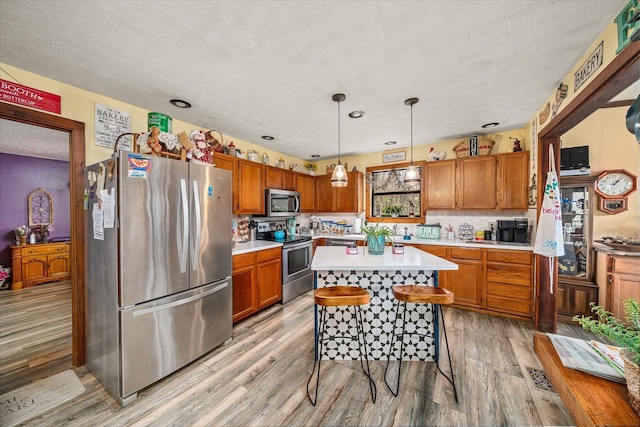 kitchen featuring light countertops, appliances with stainless steel finishes, light wood-style floors, and brown cabinets