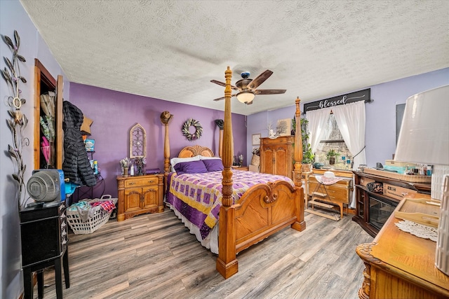 bedroom with a textured ceiling, ceiling fan, and light wood-type flooring