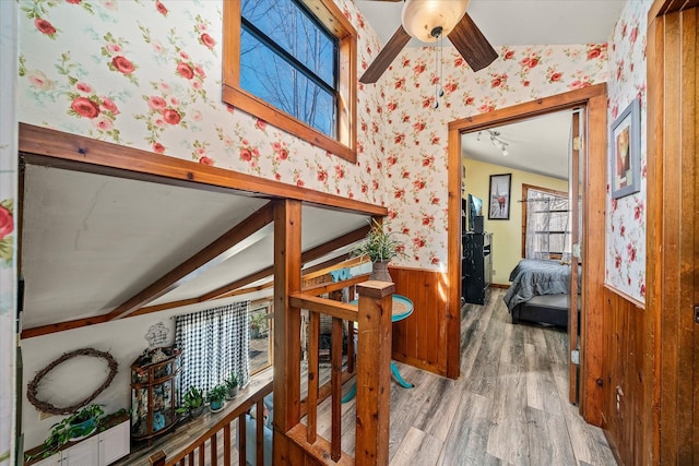 hall with wallpapered walls, wood finished floors, and wainscoting
