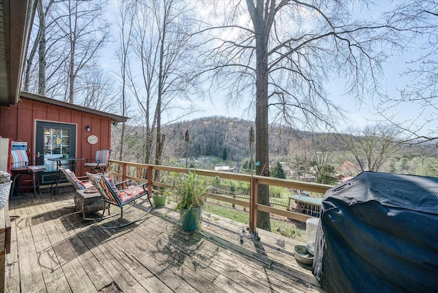 deck featuring grilling area, a mountain view, and a view of trees