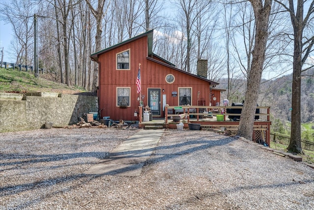 chalet / cabin with a chimney, a wooden deck, and fence