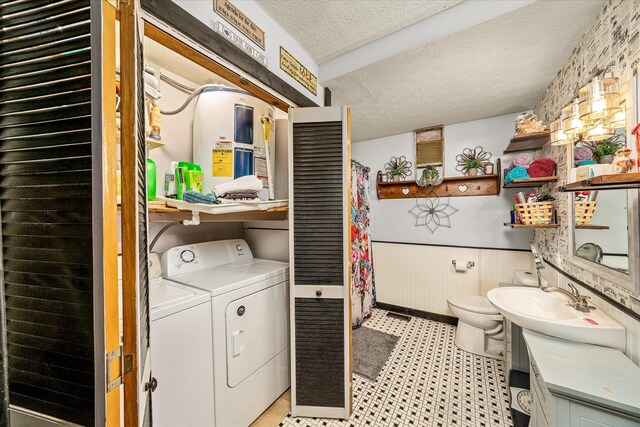 laundry room featuring a textured ceiling, laundry area, a sink, washer and dryer, and wainscoting