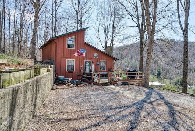 view of front of property with a chimney, a deck, and board and batten siding