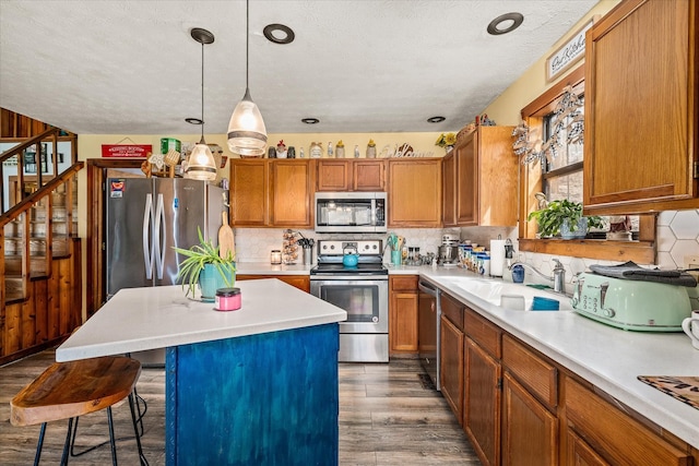kitchen featuring light countertops, tasteful backsplash, appliances with stainless steel finishes, dark wood finished floors, and brown cabinetry