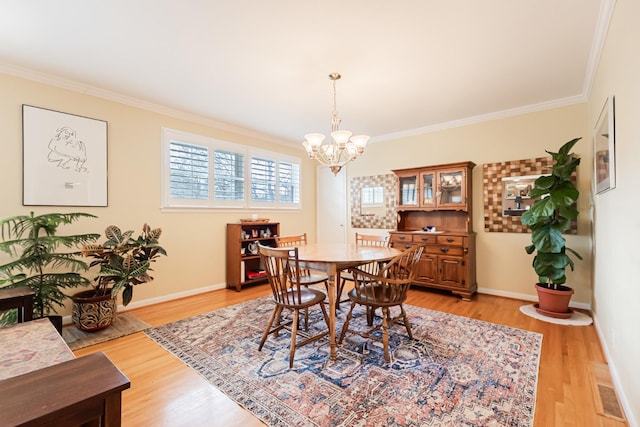 dining room featuring baseboards, a notable chandelier, crown molding, and light wood-type flooring