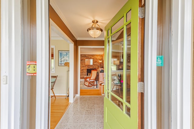 hall featuring baseboards, crown molding, and light floors