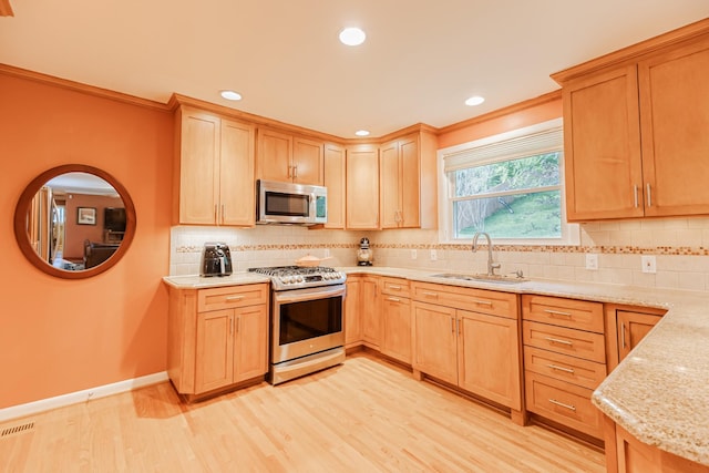 kitchen featuring a sink, light wood finished floors, light stone countertops, light brown cabinetry, and stainless steel appliances