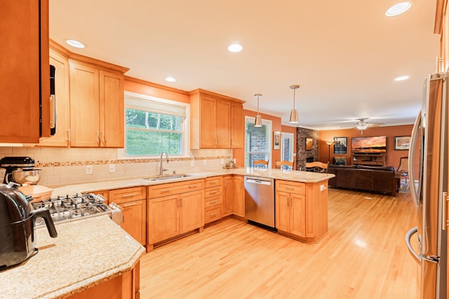 kitchen with open floor plan, a sink, a ceiling fan, a peninsula, and appliances with stainless steel finishes