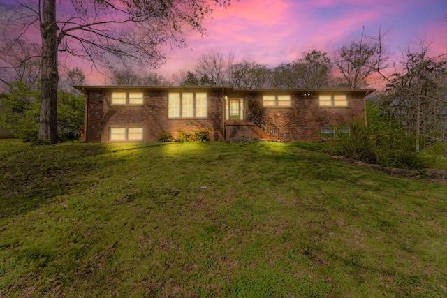 view of front facade featuring brick siding, a yard, and an attached garage