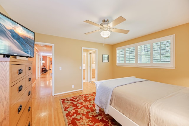 bedroom featuring baseboards, ensuite bathroom, light wood-style flooring, and ceiling fan