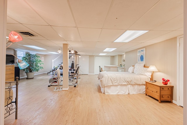 bedroom featuring baseboards, visible vents, wood finished floors, and a drop ceiling