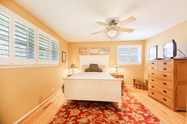 bedroom with baseboards, visible vents, light wood-style flooring, and a ceiling fan