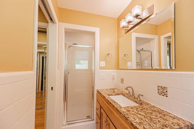 full bathroom with a shower stall, tile walls, and a wainscoted wall