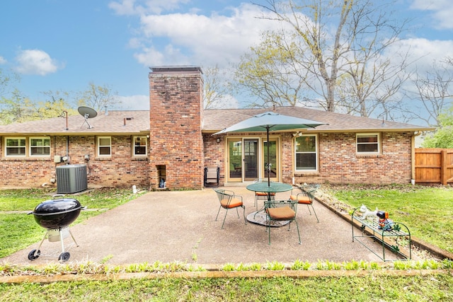 rear view of house featuring a patio area, central air condition unit, a chimney, fence, and brick siding