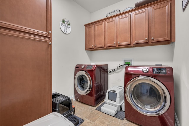 clothes washing area featuring washing machine and clothes dryer, cabinet space, baseboards, and light tile patterned floors