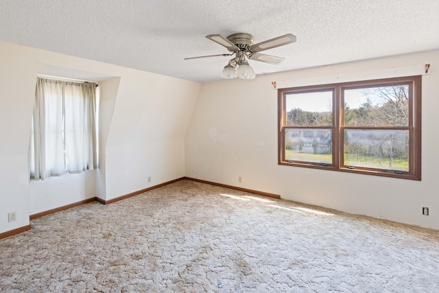 carpeted empty room with baseboards, a textured ceiling, and a ceiling fan