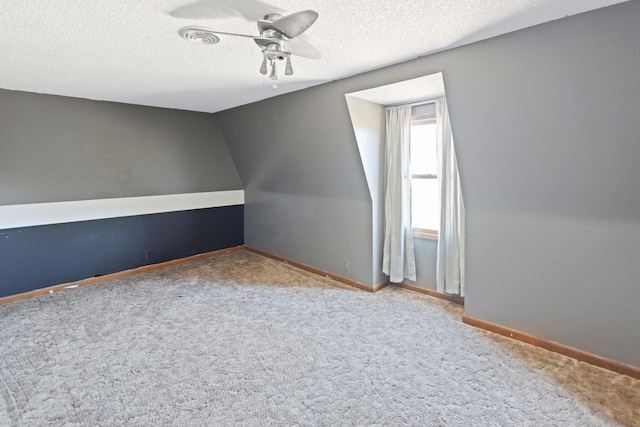 bonus room with vaulted ceiling, carpet, baseboards, a textured ceiling, and a ceiling fan