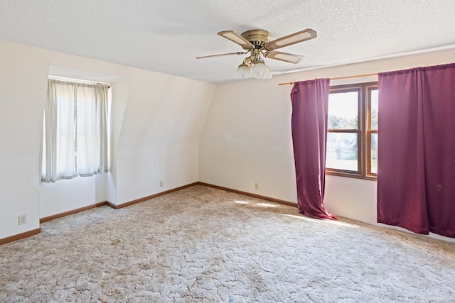 carpeted spare room with baseboards, ceiling fan, and a textured ceiling