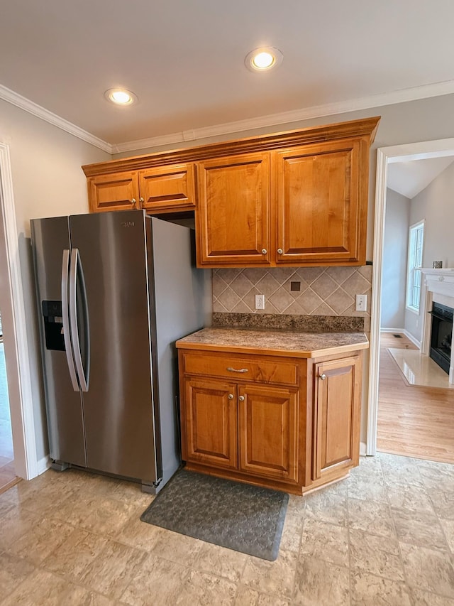 996 Iron Hill Rd, Burns, TN 37029 - kitchen with decorative backsplash, crown molding, baseboards, stainless steel fridge with ice dispenser, and brown cabinetry