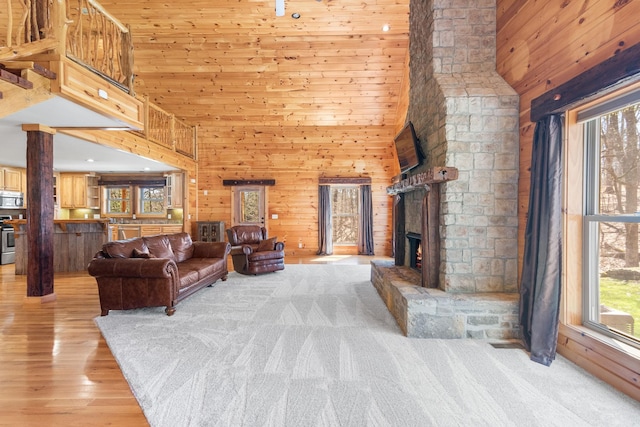 12112 Paw Paw Springs Rd, Arrington, TN 37014 - living room featuring a high ceiling, wooden walls, a fireplace, and light wood-type flooring
