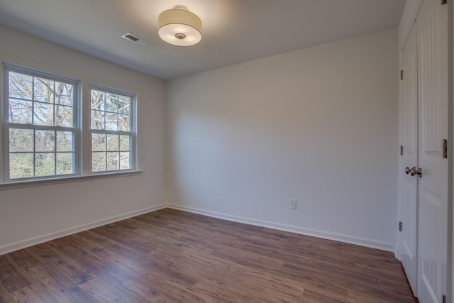 unfurnished room with dark wood finished floors and baseboards