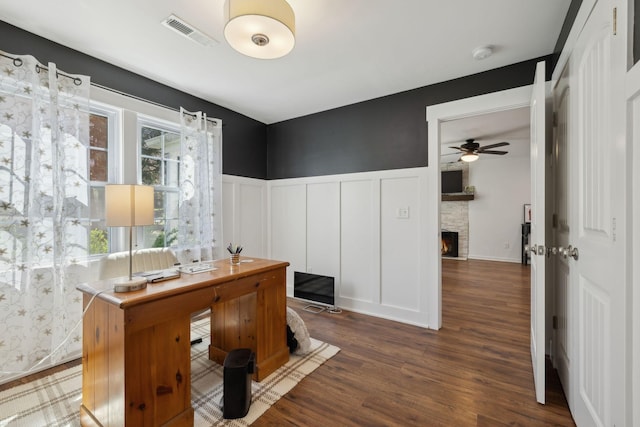 office space with a decorative wall, wood finished floors, a ceiling fan, a wainscoted wall, and healthy amount of natural light