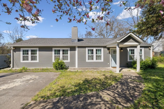 single story home with a chimney and roof with shingles