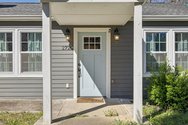doorway to property featuring roof with shingles