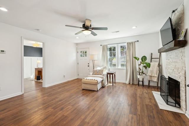 living area with dark wood-style flooring, a stone fireplace, a ceiling fan, baseboards, and recessed lighting