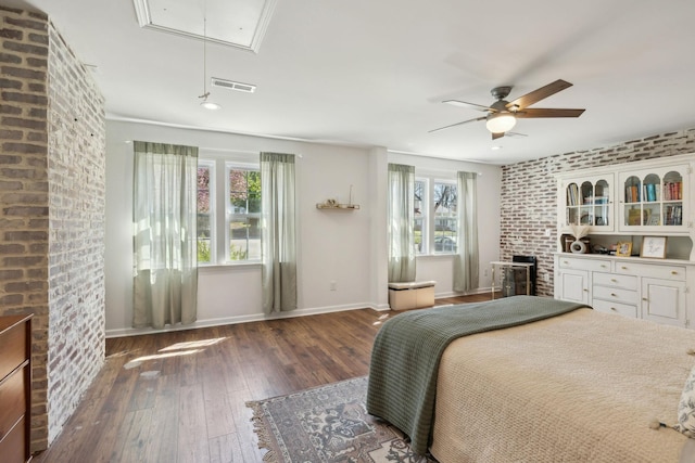 bedroom featuring attic access, hardwood / wood-style floors, brick wall, baseboards, and ceiling fan