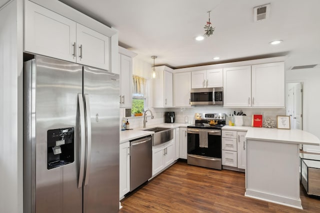 kitchen with stainless steel appliances, a sink, a peninsula, backsplash, and white cabinets