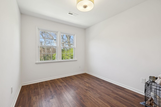 empty room featuring dark wood-type flooring and baseboards
