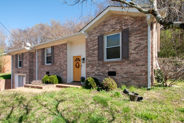 split foyer home featuring a front lawn and brick siding