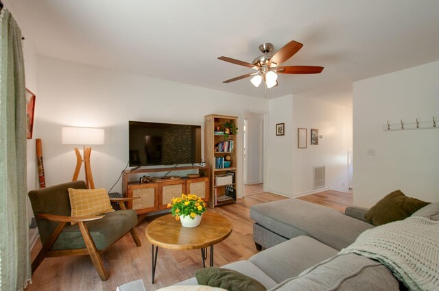 living room featuring a ceiling fan, light wood finished floors, and visible vents