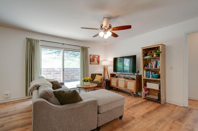 living room featuring light wood finished floors, baseboards, and ceiling fan