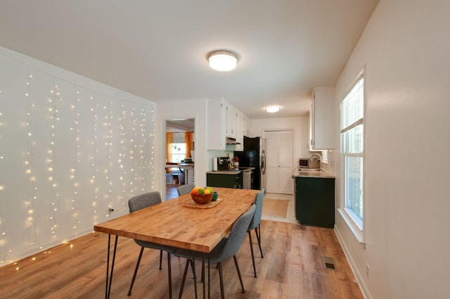 dining space featuring light wood finished floors, a wealth of natural light, visible vents, and baseboards