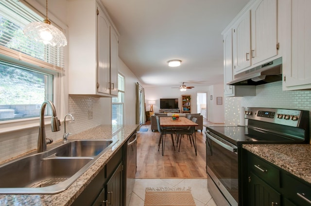 kitchen with under cabinet range hood, a sink, light tile patterned flooring, white cabinets, and appliances with stainless steel finishes