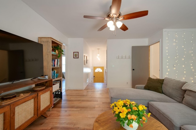 living room with baseboards, ceiling fan, and light wood-type flooring