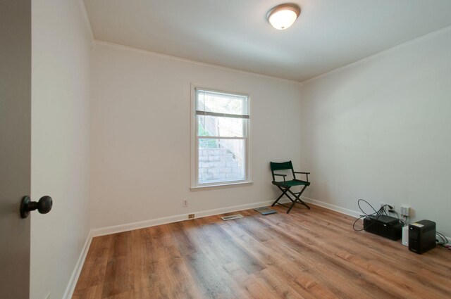 spare room with baseboards, ornamental molding, visible vents, and wood finished floors
