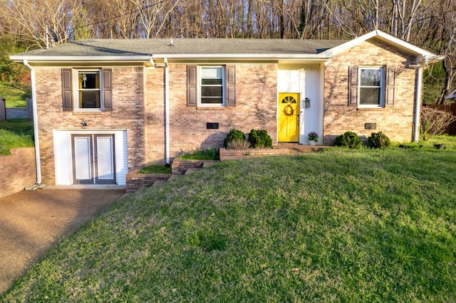view of front of house with a shingled roof, brick siding, a front yard, and french doors