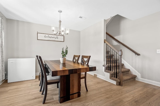 dining room with stairs, visible vents, light wood-style floors, and a chandelier