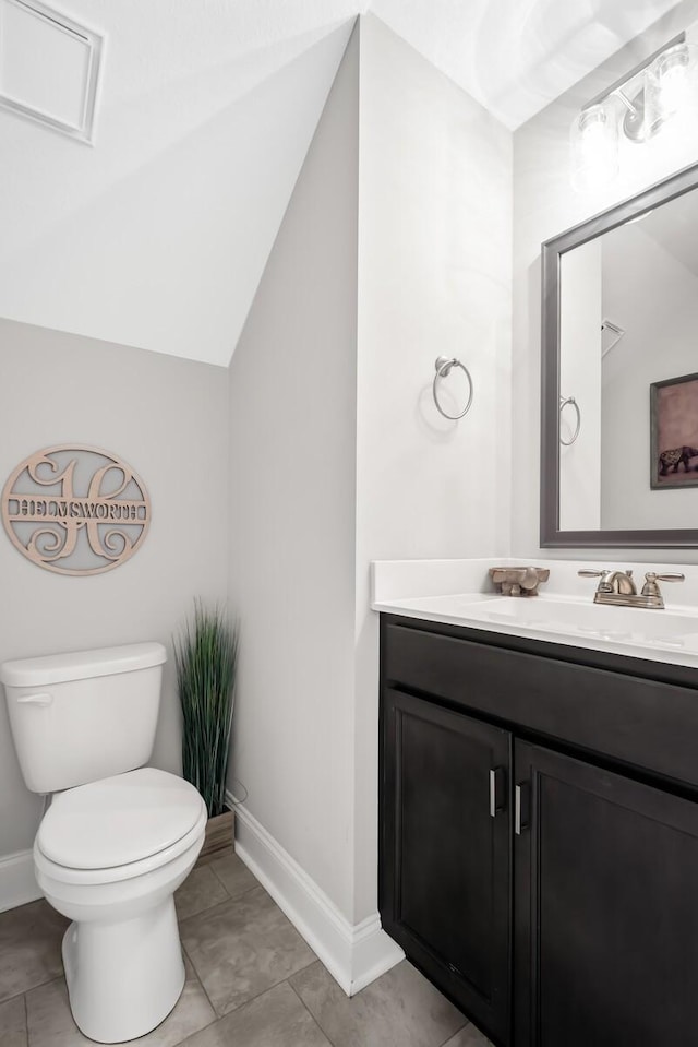 half bathroom featuring vanity, lofted ceiling, toilet, baseboards, and tile patterned floors