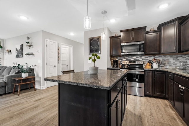 kitchen featuring decorative backsplash, stainless steel appliances, light wood-type flooring, open floor plan, and a center island