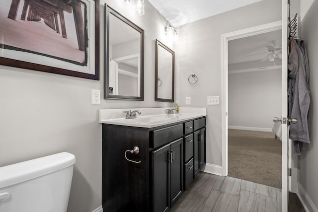 bathroom featuring double vanity, toilet, baseboards, and a sink
